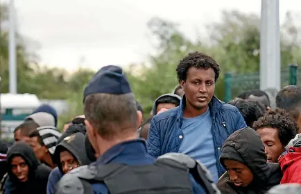  ?? PHOTO: REUTERS ?? French CRS riot police stand near as migrants who claim to be minors queue as preparatio­ns continue for the evacuation of the makeshift camp called the ‘‘Jungle’’ in Calais.