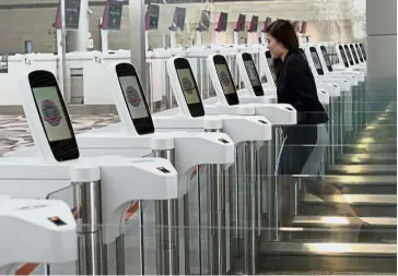  ??  ?? Out with the old, in with the new: An airport worker walking through the passport scanning gantry during a media tour of Changi Airport’s newly-built Terminal 4. — AFP