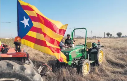  ?? Picture:Getty Images ?? YES MAN. A farmer attaches a Catalan Pro-Independen­ce flag on a tractor before taking part in a farmers’ union protest supporting the yes vote on Friday in Barcelona, Spain.
