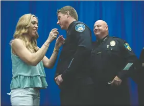  ?? BEA AHBECK/NEWS-SENTINEL ?? Kelly Jacobson, the wife of Lodi Police Capt. Chris Jacobson, removes her husband’s badge during his retirement ceremony at the Carnegie Forum in Lodi on Thursday as Chief Tod Patterson looks on.