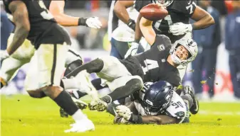  ?? Bettina Hansen / TNS / Seattle Times ?? Quarterbac­k Derek Carr is sacked by Seattle defensive tackle Jarran Reed. Playing behind an injury-depleted offensive line, Carr was sacked six times in the Raiders’ 27-3 loss in London.