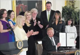  ?? Susan Walsh ?? The Associated Press President Donald Trump holds up an executive order he signed Wednesday as he is surrounded by first lady Melania Trump, second from right, Karen Pence, right, White House counselor Kellyanne Conway, third from left, Ivanka Trump,...