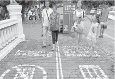  ??  ?? Residents walk on a lane painted with instructio­ns to separate those using their phones as they walk from others in southwest China’s Chongqing Municipali­ty.