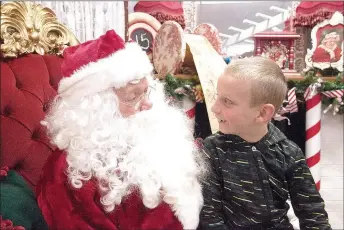  ?? LYNN KUTTER ENTERPRISE-LEADER ?? Kade Acord, 6, of Lincoln, shares his wish list with Santa at Christmas on the Square in Lincoln on Saturday night.