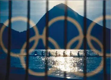  ?? AP PHOTO/DAVID GOLDMAN, FILE ?? In this 2016 file photo, rowers are seen through a screen decorated with the Olympic rings as they practice at the rowing venue in Lagoa at the 2016 Summer Olympics in Rio de Janeiro, Brazil. The Olympic Channel, a new Olympic-themed television network...