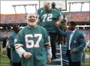  ?? LYNNE SLADKY - THE ASSOCIATED PRESS ?? In this 2007, file photo, players from the 1972 Miami Dolphins team, including guard Bob Kuechenber­g (67) and defensive tackle Bob Heinz (72), walk off the stage following a ceremony honoring the team at a game against the Baltimore Ravens at Dolphin Stadium in Miami.