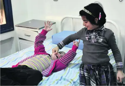  ?? George Ourfalian / AFP ?? Syrian girls who were held prisoner by opposition forces await treatment at a hospital in Aleppo.