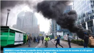  ?? ?? BRUSSELS: A man throws a projectile during a demonstrat­ion by farmers on the occasion of a EU agricultur­e ministers meeting in Brussels, on March 26, 2024. — AFP