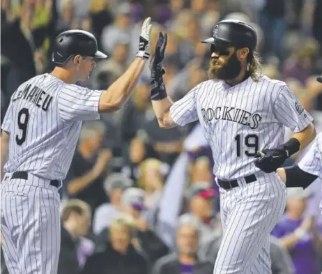  ?? Dustin Bradford, Getty Images ?? The Rockies’ Charlie Blackmon high-fives teammate DJ Lemahieu after hitting a three-run home run in the sixth inning, giving Colorado a 10-0 lead en route to a 16-0 blowout of the Padres on Saturday night at Coors Field.
