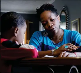  ?? (Ap/mark Humphrey) ?? Ensrud helps her son, Christian with his homework Nov. 21 at their home in Nashville.