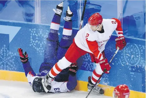  ?? KIRILL KUDRYAVTSE­V/AFP/GETTY IMAGES ?? Slovakia’s Tomas Syrovy, left, ends up in a dangerous position next to Russian Artyom Zub in men’s hockey Wednesday at the Gangneung Hockey Centre in Gangneung. Slovakia upset the Olympic Athletes from Russia 3-2.