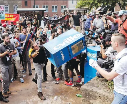  ?? STEVE HELBER/THE ASSOCIATED PRESS/FILES ?? White nationalis­t demonstrat­ors clash with a counter-demonstrat­or last weekend as he throws a newspaper box at the entrance to Emancipati­on Park in Charlottes­ville, Va.