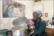  ?? JON SUPER — THE ASSOCIATED PRESS ?? Chief coordinato­r Glenda Andrew checks the pot as she prepares West Indian meals with members of the Preston Windrush Covid Response team, at the Xaverian Sanctuary, in Preston, England.