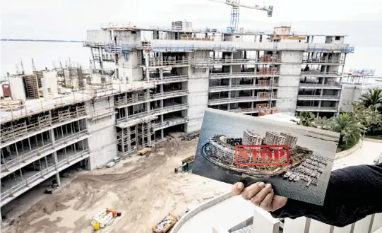  ?? ALIE SKOWRONSKI askowronsk­i@miamiheral­d.com ?? A Grove Isle resident who has been fighting against the new condo building under constructi­on holds a pamphlet while standing on an eighth-floor condo in Building 3. Some Grove Isle residents have sued the city of Miami, alleging the building wasn’t properly permitted by the city. The city is seeking to dismiss the suit.