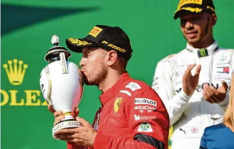 ?? Foto: Attila Kisbenedek, afp ?? Küsschen für den Pokal: Sebastian Vettel muss sich auf dem Hungarorin­g mit dem zweiten Platz hinter Lewis Hamilton (rechts) zufriedeng­eben.