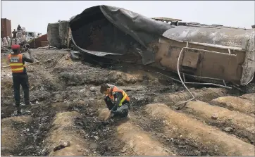  ??  ?? Pakistani rescue workers examine the site of an oil tanker explosion Sunday at a highway near Bahawalpur, Pakistan. An overturned oil tanker exploded killing more than 150people who had rushed to the accident to gather leaking fuel.