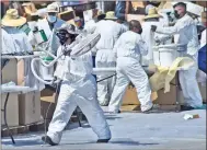  ?? Dan Watson/The Signal ?? Workers unload old cans of paint from waiting cars as another carries a discarded electric fan to a dumpster during the Household Hazardous Waste Roundup at COC Saturday.