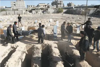  ?? Abdulmonam Eassa / AFP / Getty Images ?? Syrians bury the victims of an air strike on the rebel-held town of Arbin on the outskirts of Damascus. The government and opposition resumed peace talks in Geneva on Tuesday.