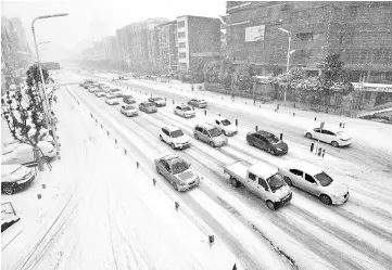  ??  ?? Photo shows traffic on a snow-covered street in Fuyang, in China’s eastern Anhui province. — AFP photo