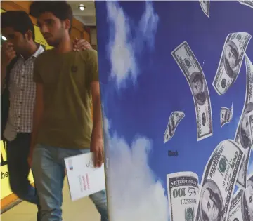  ??  ?? Pakistani youths are seen walking past a currency exchange shop in Islamabad. Pakistan’s next government, to be chosen in a July 25 election, faces growing fears of a balance of payments crisis with speculatio­n it will have to seek its second IMF...