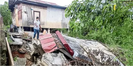  ??  ?? Unstable ground: Roslan showing the collapsed foundation of his house at Pengkalan Syed Agil, Sungai Golok. — Bernama