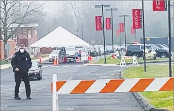  ?? John Kovach / Hearst Connecticu­t Media ?? A New Canaan police officer wears a protective mask while monitoring a coronaviru­s testing site.