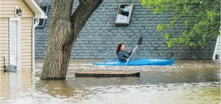  ??  ?? People use kayaks to assess the damage to homes in Beaverton, Michigan, on Tuesday.