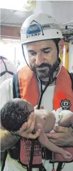  ?? FO ?? Ein Arzt der Organisati­on Ärzte ohne Grenzen h ein Baby in den Händen, das von einem Schlau boot im Mittelmeer gerettet wurde.