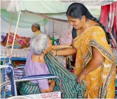  ??  ?? Yakub Bee helps dress a handicappe­d elderly lady, resident at the Sahrudaya old age home on Monday. —DC