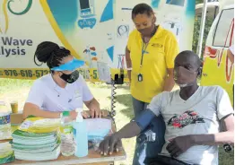  ??  ?? New Wave Dialysis patient technician Maria Blake (left) does a blood pressure check on Allan Vanriel during a fundraiser in his honour at the Negril Tactical Shooting Range in Westmorela­nd recently. Looking on is Christine Green, operator of the range.