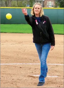  ?? Westside Eagle Observer/RANDY MOLL ?? Kristin Ferguson of Gentry delivers a ceremonial first pitch prior to the “No One Fights Alone” softball game between Gentry and Greenland on April 3 in Gentry. Ferguson, a breast cancer survivor, threw the pitch to her daughter, freshman catcher...