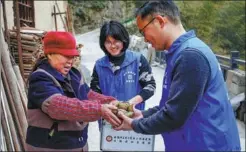  ?? SHI YALEI / XINHUA ?? During a follow-up visit, a villager gives Zhang Jianming (right) and Xu Xiaochan (center) her homemade rice dumplings.