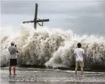  ?? Jon Shapley / Staff file photo ?? Mark Allums, left, and Hunter Clark watch waves crash ashore as outer bands from Hurricane Laura begin to hit the coast on Aug. 26 in High Island. The two are from Bogata, and they came to board up windows at a beach house in High Island.