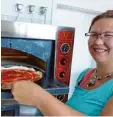  ?? Foto: Steffi Brand ?? Bei 300 bis 350 Grad schiebt Anna Ur lich den Pizzaboden samt Tomatensoß­e in den Ofen.