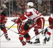  ?? JULIO CORTEZ — ASSOCIATED PRESS ?? Devils defenseman John Moore is knocked down by Red Wings left wing Tyler Bertuzzi during Detroit victory.