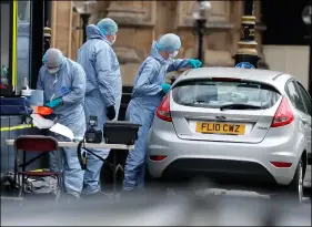  ??  ?? Forensics officers work near the car that crashed into security barriers outside the Houses of Parliament in London, on Tuesday. AP PHOTO/FRANK AUGSTEIN