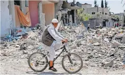  ?? | AFP ?? A MAN rides a bicycle past the rubble of a collapsed building in the Maghazi camp for Palestinia­n refugees in the central Gaza Strip yesterday.