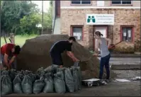  ?? The Associated Press ?? SANDBAGS: Andrea Dube, right, and John Flemming fill sandbags as a precaution for the potential of more flooding from rain storms on Friday in New Orleans. With debris from last weekend's flash flood still piled up on sidewalks and their city under a...