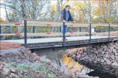  ?? ERIC MACCARTHY/JOURNAL PIONEER ?? Elton Ellis, co-ordinator of West Point and Area Watershed Associatio­n, checks the water flow beneath a new bridge deck his associatio­n recently installed with help from volunteers and the Wildlife Conservati­on Fund.