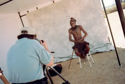  ??  ?? Backstage Harry De Zitter, classe 1949, fotografo belga cresciuto in Sudafrica, mentre fotografa un componente della tribù Himba alla fine degli anni Novanta La tribù, situata nel nord della Namibia, scampata alla colonizzaz­ione tedesca, rispettava modi tradiziona­li, incontamin­ati