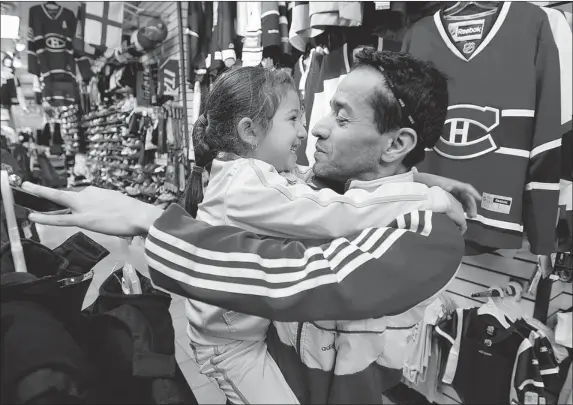  ?? PIERRE OBENDRAUF/ THE GAZETTE ?? With business at his sport merchandis­e store on Ste. Catherine St. down significan­tly, Santana Enrique brings 5-year-old daughter, Yasmine, to work to save on babysittin­g costs.