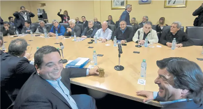  ??  ?? Otros tiempos. El ministro de Trabajo, Jorge Triaca, sonríe en una reunión con sindicalis­tas. La reforma laboral que impulsa el Gobierno ahora se aplaza.
