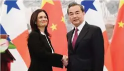  ?? — AFP ?? BEIJING: Panama’s Vice President and Foreign Minister Isabel de Saint Malo shakes hands with Chinese Foreign Minister Wang Yi during a joint press briefing after the two signed a joint communique agreeing to establish diplomatic relations yesterday.