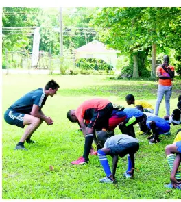  ?? CONTRIBUTE­D ?? Coach Carlos Gustavo Albert Garcia (left) of the Real Madrid Foundation conducting training drills with youngsters in western Jamaica at a football clinic in Negril at the weekend.