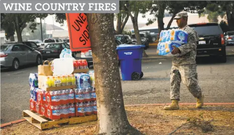  ?? Gabrielle Lurie / The Chronicle ?? Sgt. Narayan Aman of the 870th Military Police Company carries donated water outside Petaluma Community Center.