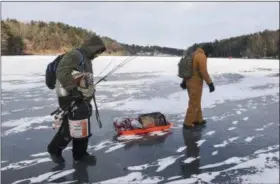  ?? DAVID MCKEOWN — REPUBLICAN-HERALD VIA AP ?? Chris Fidler, left, of Halifax, and Ben Reigert, of Reading, walk out onto the ice at Sweet Arrow Lake, to fish on Saturday in Pine Grove, Pa. Freezing temperatur­es since December 26 have made for ideal ice fishing conditions.