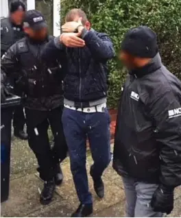  ??  ?? Arrest: A suspect shields his face as he is led away yesterday