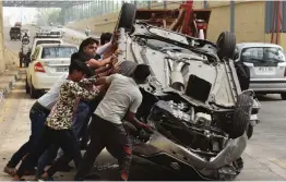  ?? — PTI ?? A group of men try to upright an overturned car after the driver lost control and crashed into the wall of Rajiv Chowk underpass, in Gurugram on Thursday.