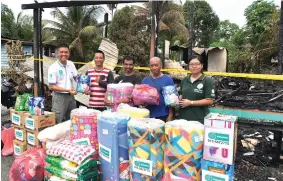  ??  ?? Wan (left) and Law (right) hand over some food items to heads of the three families whose houses were razed by fire at Bintawa Hilir.