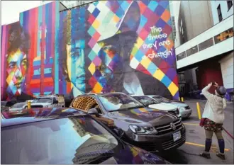  ?? CRAIG LASSIG / REUTERS ?? Mandy Fallen of St. Cloud photograph­s a mural of Bob Dylan, the 2016 Nobel Prize winner in literature, in Minneapoli­s, Minnesota on Thursday. The mural was created by Brazilian artist Eduardo Kobra and his team.